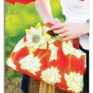 May include: A red handbag with a white floral pattern and a yellow flower embellishment. The handbag has a brown handle and a white button on the flower. The text "marlo bloom Handbag" is printed on the packaging.