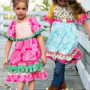 May include: Two girls wearing colorful peasant dresses. The girl on the left is wearing a pink and green dress with a white floral pattern. The girl on the right is wearing a blue and white dress with a floral pattern. The text "Vintage Jane peasant top and dress #28" is at the bottom of the image.