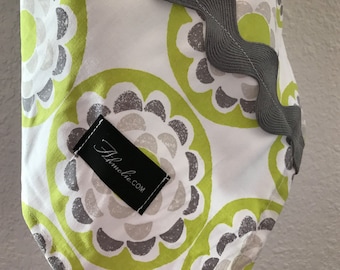 May include: A white fabric with a green and gray floral pattern. The fabric has a gray scalloped edge and a black label with the text "Abloomie.com".