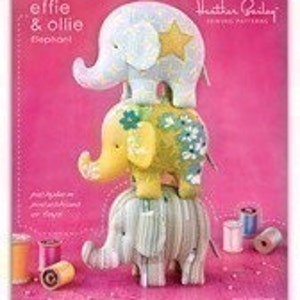 May include: Three stackable plush elephant sewing patterns by Heather Bailey. The elephants are in shades of gray, yellow, and blue with embroidered details. The pattern is called "Effie & Ollie Elephant".