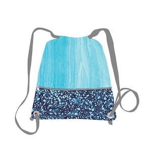 May include: A drawstring backpack featuring a two-tone design. The upper section displays a light blue watercolor-style pattern, while the lower zippered pocket features a dark blue and light blue speckled print. It includes grey shoulder straps.