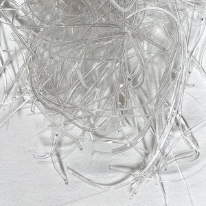May include: A pile of clear plastic tubing, tangled and overlapping. The tubing is flexible and appears to be used for crafting or other projects.
