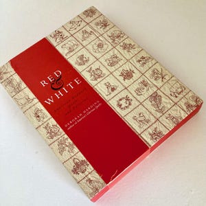 May include: A hardcover book titled Red & White: American Redwork Quilts and Patterns by Deborah Harding. The cover features a central red vertical band with white text, flanked by cream-colored panels with a grid of brown line drawings.