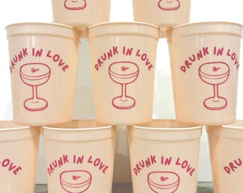 May include: A stack of pink plastic cups with the text "Drunk in Love" and a pink martini glass graphic printed on each cup.