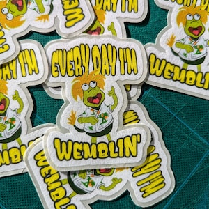 May include: A collection of stickers featuring a green cartoon character with yellow hair and a white shirt with a tropical design. The stickers have the text "EVERY DAY I'M WEMBLIN'" in yellow.