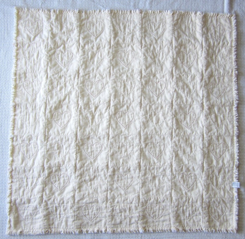 May include: A white quilted blanket with a subtle heart pattern stitched into the fabric.