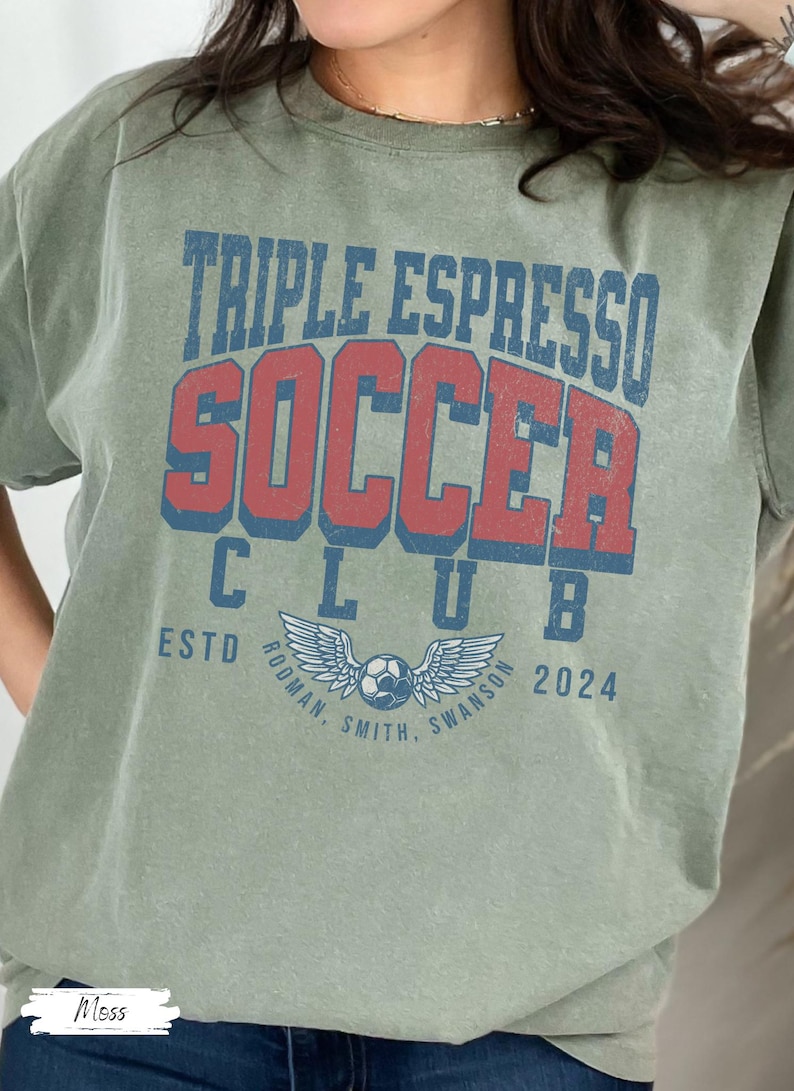 Op de afbeelding: Een groen T-shirt met de tekst "Triple Espresso Soccer Club" in rode en blauwe letters. De tekst "Estd 2024" staat onder de clubnaam. Een voetbal met vleugels bevindt zich in het midden van het shirt.