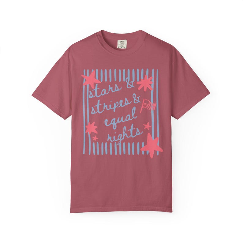 Puede incluir: Camiseta granate con las palabras "stars & stripes & equal rights" en escritura azul claro y un borde a rayas azul claro a juego. Estrellas rosas y una peque&ntilde;a bandera americana.