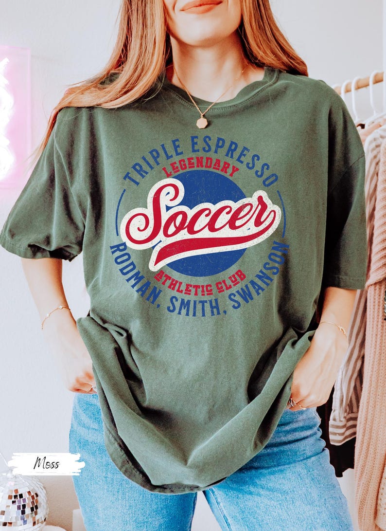 Puede incluir: Una camiseta verde con un dise&ntilde;o gr&aacute;fico de estilo vintage que incluye las palabras "Triple Espresso Legendary Soccer Rodman, Smith, Swanson Athletic Club".
