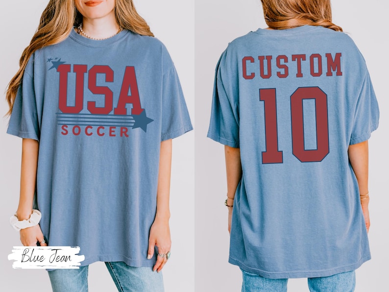 May include: A light blue t-shirt with the text "USA SOCCER" in red. The front of the shirt has a star graphic. The back of the shirt has the word "CUSTOM" above the number "10" in red.