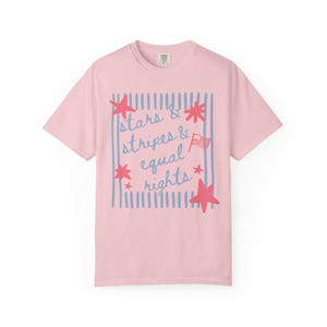 Puede incluir: Camiseta rosa claro con el texto "stars & stripes & equal rights" en azul y rojo. El dise&ntilde;o incluye estrellas rojas, rayas azules y una peque&ntilde;a bandera americana.