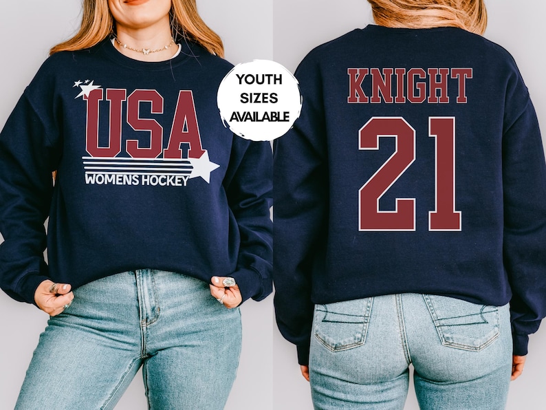 May include: Navy blue sweatshirt with "USA WOMENS HOCKEY" in maroon and white. The front design includes stars. The back features "KNIGHT 21" in maroon. Youth sizes available.