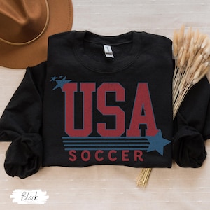 May include: Black sweatshirt with a red, white, and blue graphic that says "USA SOCCER" with stars.