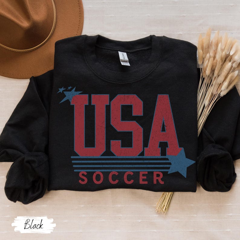 May include: Black sweatshirt with a red, white, and blue graphic that says "USA SOCCER" with stars.