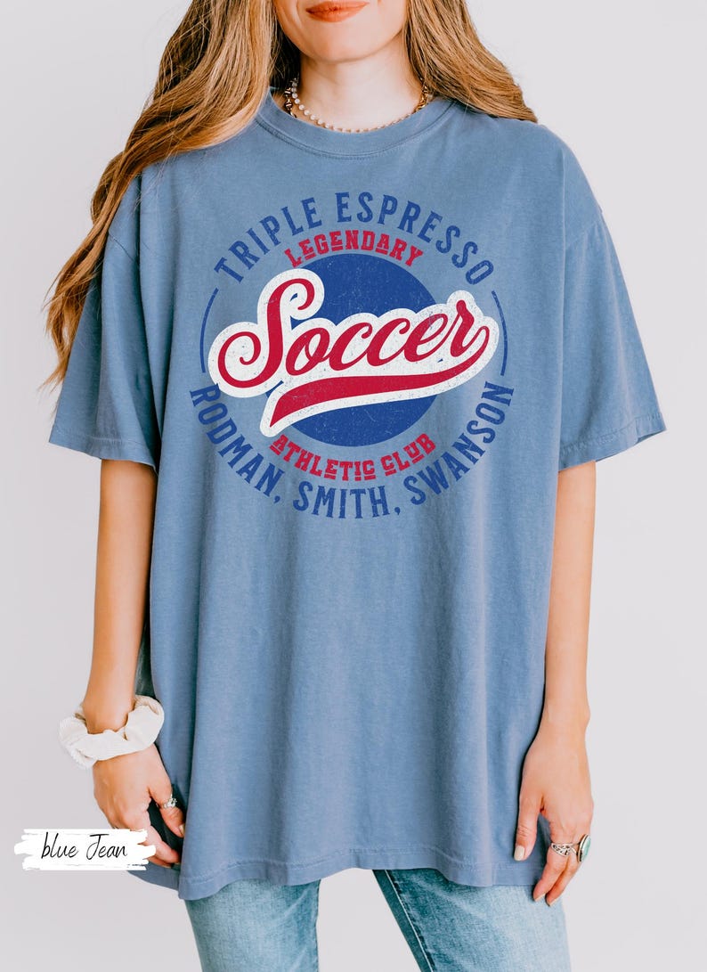 Puede incluir: Una camiseta de gran tama&ntilde;o de color azul vaquero con un dise&ntilde;o gr&aacute;fico de estilo vintage que incluye el texto "Triple Espresso Legendary Soccer Rodman. Smith. Swanson Athletic Club".