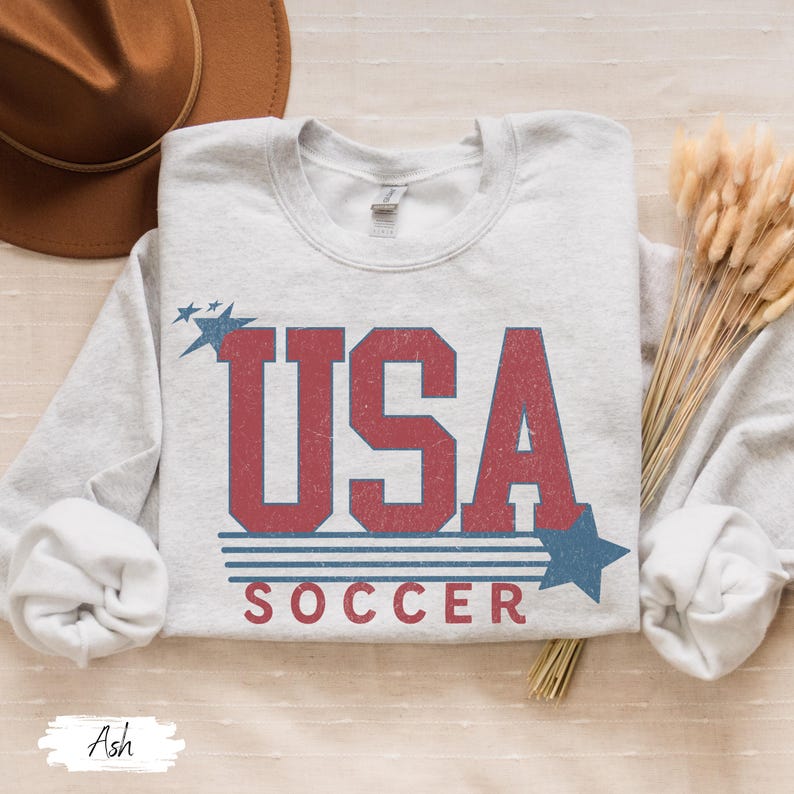 May include: A gray sweatshirt with a vintage-style graphic of "USA SOCCER" in red and blue with stars.
