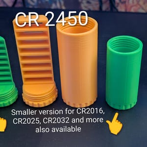May include: Four 3D-printed battery holders in green and orange. The text "CR 2450" is at the top. The text "Smaller version for CR2016, CR2025, CR2032 and more also available" is at the bottom.