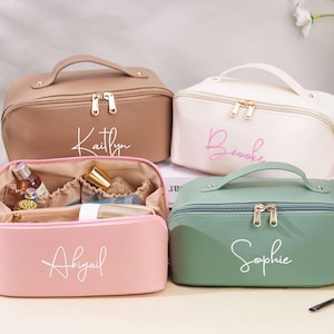 May include: Four personalized makeup bags with zipper closures and handles. The bags are in pink, brown, white, and green. The names "Abigail", "Kaitlyn", "Brooke", and "Sophie" are written on the bags in white script.