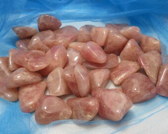 May include: A collection of tumbled rose quartz stones in various sizes and shapes. The stones are a pale pink color and have a smooth, polished finish.