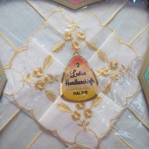 May include: Two white handkerchiefs with gold floral embroidery, packaged in a decorative box. The handkerchiefs have scalloped edges and are labeled "Ladies Handkerchiefs, Full Size."