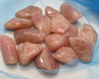 May include: A collection of tumbled rose quartz stones in various sizes and shapes. The stones are a pale pink color and have a smooth, polished finish.