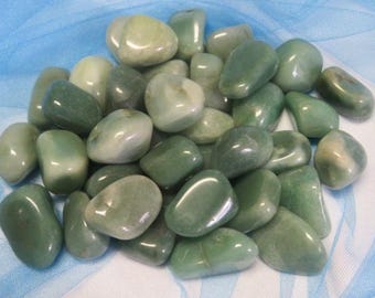 May include: A collection of smooth, polished green jade stones. The stones vary in shades of green, from light to dark, and have a glossy, reflective surface. They are tumbled and rounded, with a natural, organic shape.