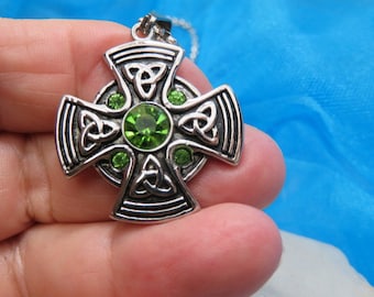May include: Silver Celtic cross pendant with green crystal accents. The cross features a knot design and is a popular Irish symbol.