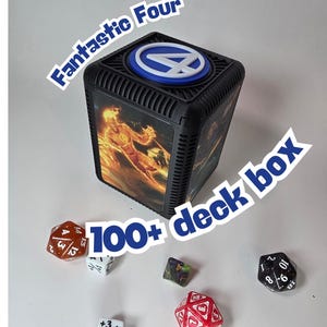 May include: Black deck box with the Fantastic Four logo and images of the Human Torch. The box is labeled "100+ deck box". Several dice are scattered around the box, including a red D20 and a black D10.