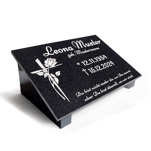 Könnte beinhalten: Ein schwarzer Granitstein mit einem weißen Kreuz und einer Rose, die darauf graviert sind. Die Inschrift lautet "Leona Muster geb. Mustermann * 12.11.1954 †15.12.2024 Du bist nicht mehr da, wo Du warst, aber Du bist überall, wo wir sind."