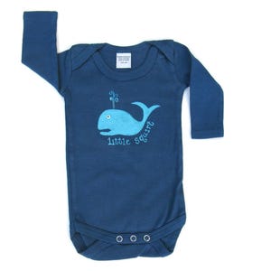 May include: A dark blue long-sleeved baby onesie with a blue whale graphic and the text "little squirt".