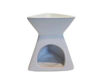 Puede incluir: Un difusor de aceite triangular de cerámica blanca con un esmalte azul claro. El difusor tiene una pequeña abertura en el centro para una vela de té.