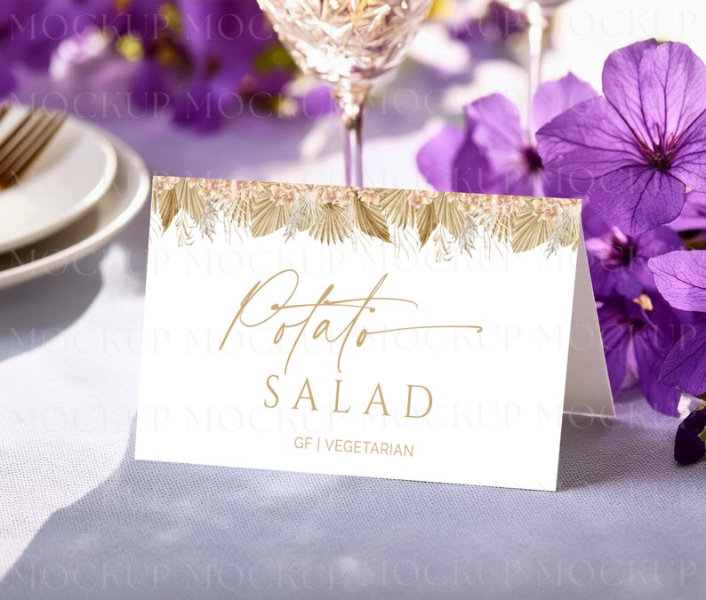 May include: A white folded card with gold text that reads "Potato Salad". The card has a decorative border of dried flowers and foliage. The bottom of the card reads "GF | Vegetarian".