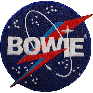 Op de afbeelding: Een ronde geborduurde patch met een donkerblauwe achtergrond en de witte tekst BOWIE. Het ontwerp bevat een rode bliksemschicht, een dunne blauwe orbitale lijn en kleine witte sterachtige stippen verspreid over het oppervlak.