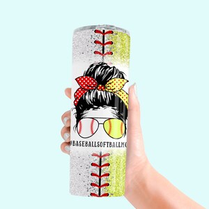 May include: A white tumbler with a glitter finish and a baseball and softball design. The tumbler features a woman with a bun and a red and yellow polka dot headband. The text "#BASEBALLSOFTBALLMOM" is printed on the tumbler.