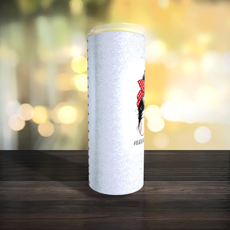 May include: White tumbler with a glitter finish and a baseball-themed design. The design features a cartoon girl with a red and white polka dot bow, holding a baseball bat and a baseball. The text "#BASEBALL" is printed below the design.