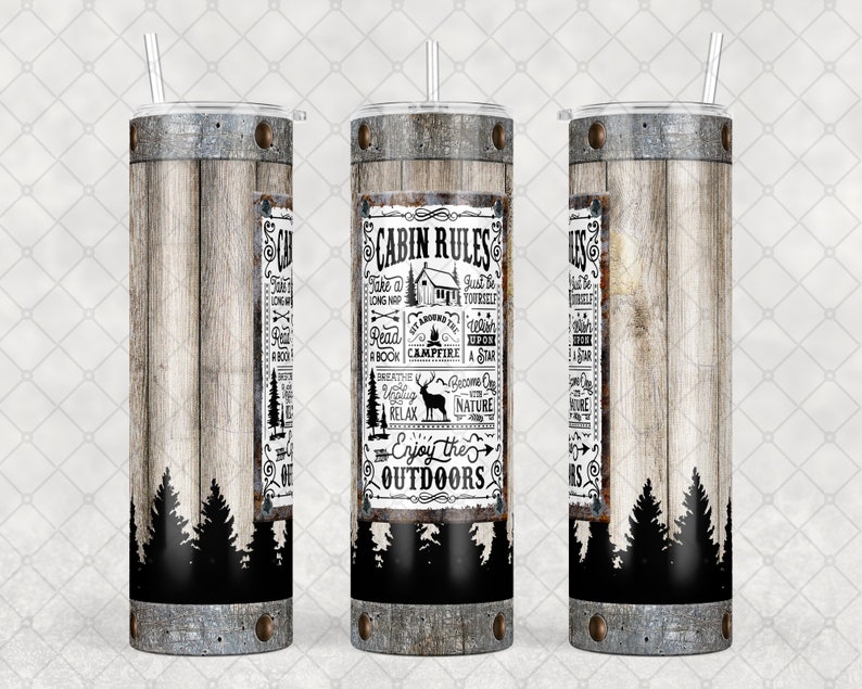 May include: A stainless steel tumbler with a wooden plank design and the words "Cabin Rules" in a rectangular frame. The tumbler has a black forest silhouette at the bottom and a silver lid with a straw.