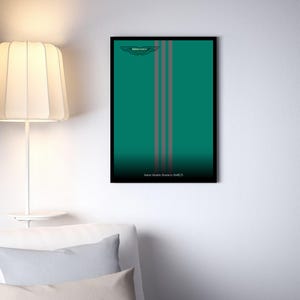 Puede incluir: Una lámina de arte mural rectangular enmarcada con un fondo verde azulado intenso y tres franjas verticales grises. El logotipo de Aston Martin está en la parte superior y el texto Aston Martin Aramco AMR23 está impreso en blanco abajo.