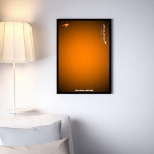 Może przedstawiać: Oprawiony plakat z pomarańczowym gradientem i czarną obwódką. Logo McLarena znajduje się w lewym górnym rogu, ze słowem "McLaren" i "Formula 1 Team" w białym tekście. Słowa "McLaren MCL35" znajdują się na dole.