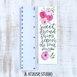 May include: A watercolor bookmark with pink floral accents and the text "Sweet friendships refresh the soul Proverbs 27:9." The bookmark is approximately 6 inches long and features green and pink calligraphy. The artist's name, A. Krause Studio, is at the bottom.