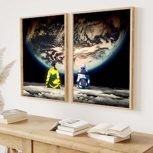 May include: Two framed art prints depict anime-style figures seated on a lunar surface, gazing at a large, detailed planet. The prints have wooden frames and are displayed on a white wall. The artwork features a dark color palette with vibrant accents.