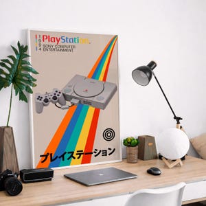 May include: A framed poster featuring a PlayStation console and controller with a rainbow design. The poster includes the text "PlayStation" and Japanese characters. The color scheme includes beige, orange, blue, and gray.