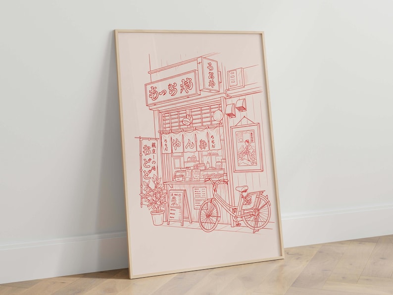 May include: Red line art print of a Japanese restaurant with a bicycle parked outside. The print features a detailed illustration of the shop's facade, signage, and interior details. A potted plant and a menu board are also visible.
