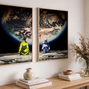 May include: Two framed art prints depict figures seated on a moon-like surface, gazing at Earth. The artwork features a dark space background with a vibrant planet. The figures are in yellow and blue attire. The frames are a light wood color.