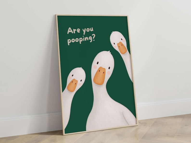 May include: A rectangular wall art print featuring three white geese with orange beaks against a dark green background. The text "Are you pooping?" is printed in white in the upper left corner. The geese have simple black eyes and pink cheeks.