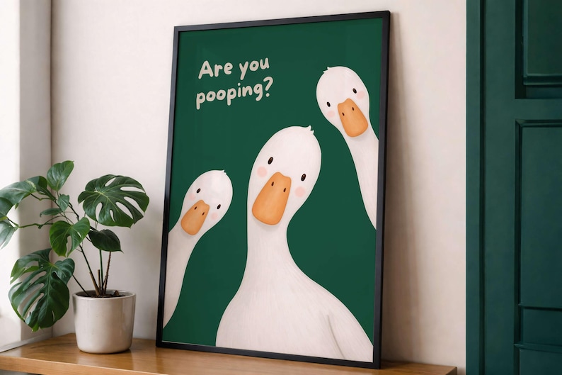 May include: A framed wall art print featuring three white geese with orange beaks against a dark green background. The text "Are you pooping?" is printed in white in the upper left corner. The geese have simple black eyes and pink cheeks.