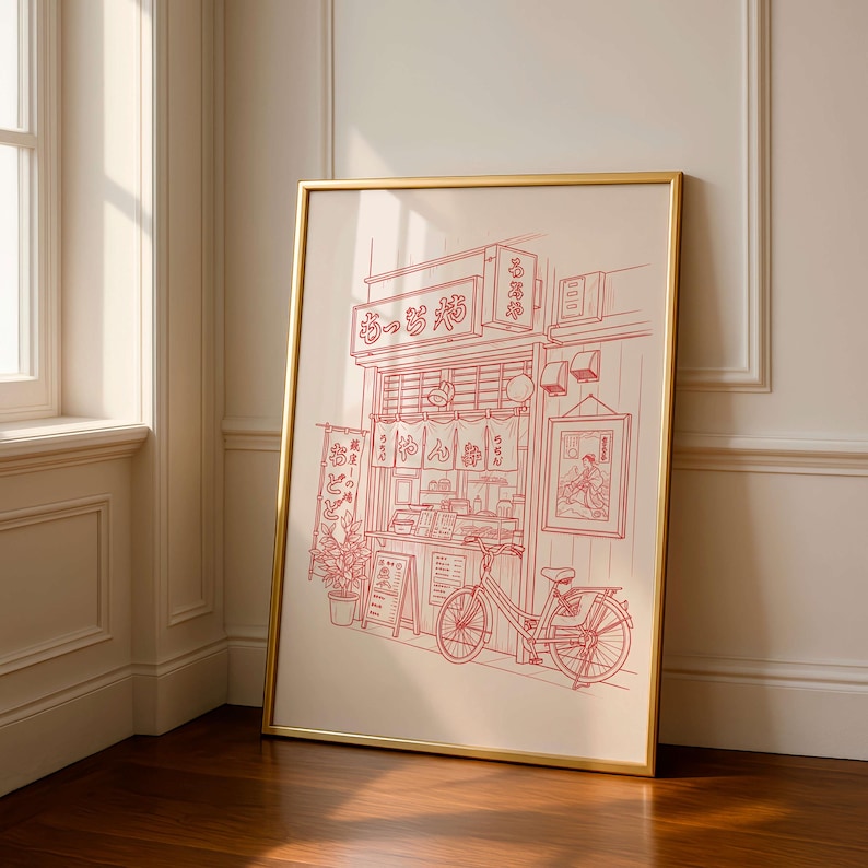 May include: A framed print featuring a red line drawing of a Japanese ramen shop with a bicycle parked in front. The shop has a sign in Japanese and a small menu board. The artwork is in a gold frame.