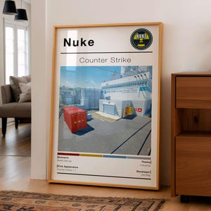 May include: A framed poster featuring the "Nuke" map from Counter-Strike. The image shows a detailed illustration of the map's industrial setting, including a red container and a nuclear power plant. The poster includes the game's logo and text.
