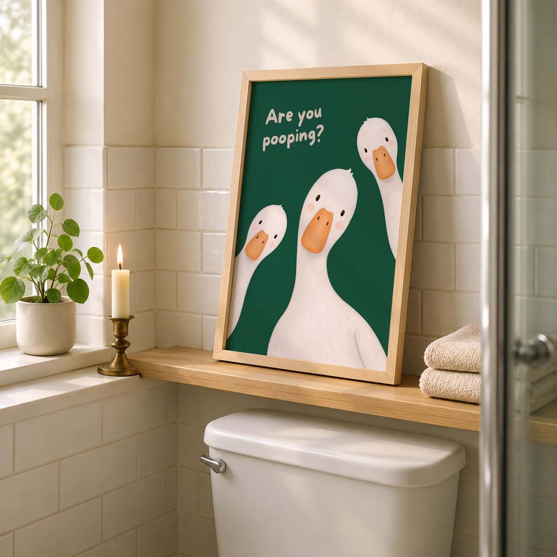 May include: A framed wall art print featuring three white geese with orange beaks against a dark green background. The text "Are you pooping?" is printed in white in the upper left corner. The illustration has a clean, simple aesthetic.