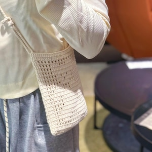 以下が含まれることがあります： 白いワッフルニットのシャツとグレーのスウェットパンツを着た人が、白いクロシェバッグを肩にかけています。