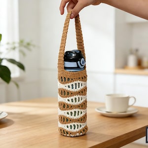 May include: A handmade crochet water bottle holder in shades of brown, white, and green. The holder features a decorative openwork design and a sturdy handle. A black and blue water bottle is inside the holder.